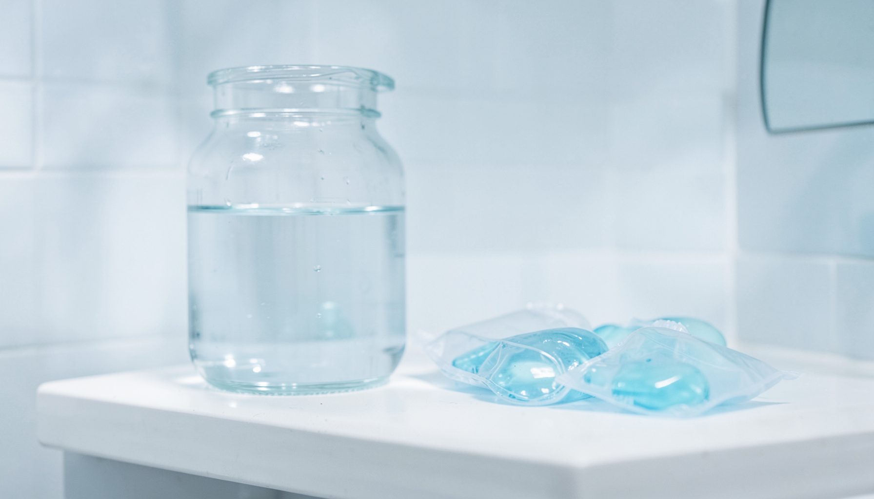 A distilled water jug and saline packets on a bathroom shelf, soft diffused lighting, clean white and blue palette