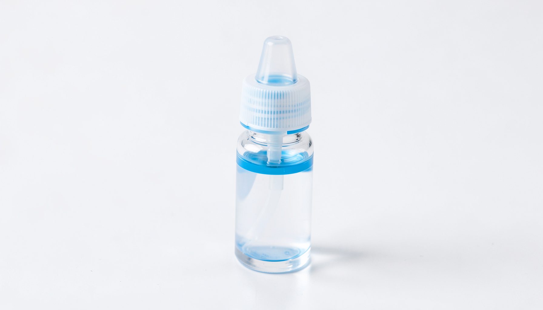 Close-up of a clear squeeze bottle with blue accents on a clean white surface, conveying hygiene and modern nasal care