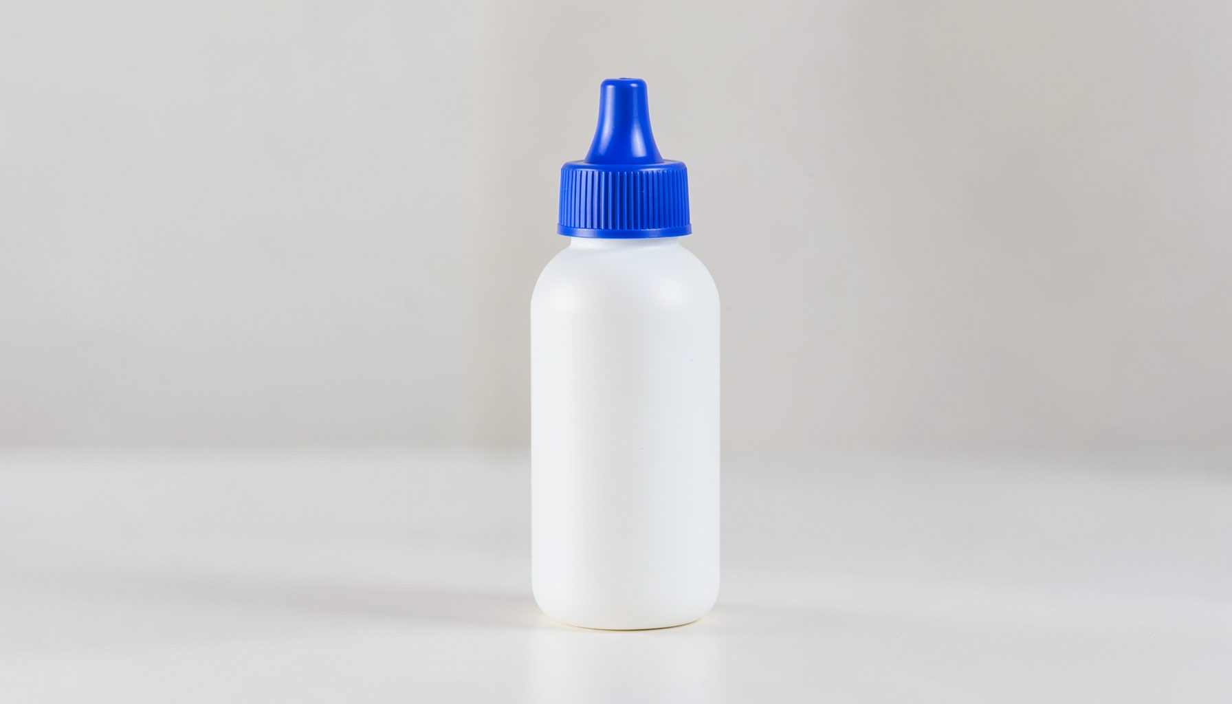 A clean white squeeze bottle with a blue cap on a light surface, soft natural lighting, modern medical-product aesthetic